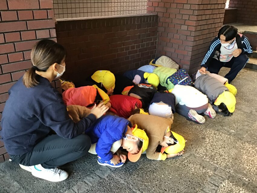 今日は竜巻を想定した避難訓練をしました。
散歩に行く途中に竜巻が発生した連絡を受けて、近くのビルに避難すると「何で外に逃げないの？」と不思議に思う子が大勢いました。
「強い風が集まって竜巻が起こるから、外にいると車も木もみんなも飛ばされてしまうからだよ。」と話すと
「そうなんだ！」と理解している様子でした。
市ヶ谷保育園では様々な災害の訓練を通して、自然が及ぼす影響を子どもたち自身が考え、関心が持てるようにしています。
避難訓練の後は天気も良かったので、近くの公園で思い切り遊びました♪