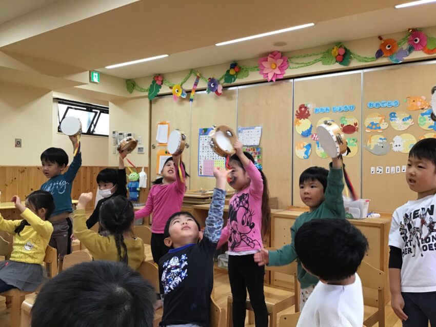 朝の時間に先生が楽器の準備をしていると、興味津々の子どもたち。
音楽教室で楽器遊びをする事に気が付き、「早くやりたい～」と楽しみにしていました。
音楽教室が始まると、ピアノに合わせて鈴やタンバリン、カスタネットをしました。
3歳の時にもやっていたので、覚えていたのもあってあっという間に曲に合わせて鳴らすことが出来ました♪
久しぶりの楽器遊びが楽しかったようで、「またやりたいね！」とニコニコしながらお話していました。
市ヶ谷保育園では様々な楽器に触れ、音を聞く中でリズム感を養い、音の楽しさや美しさが感じられるようにしています。
