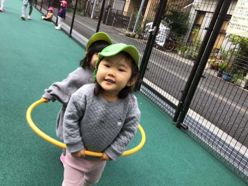 １歳児さんは最近、お部屋でも戸外でもお友だちと一緒に遊ぶことの楽しさを感じられるようになってきました。<br />
フラフープに二人で一緒に入って進むことも楽しんでいます♪