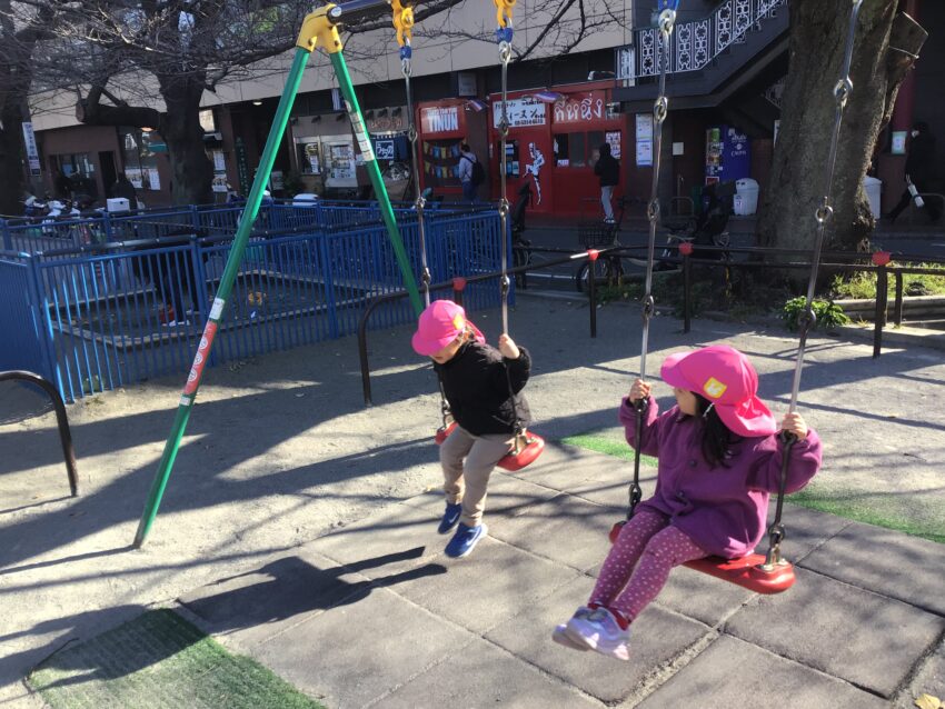 外堀公園にあるブランコの漕ぎ方を先生に教えてもらいました。<br />
「伸ばすー、曲げるー」の声を真似しながら足を伸ばしたり曲げたりする2歳児さん。<br />
だんだんブランコが大きく揺れて高い位置になってくると満面の笑顔に♪