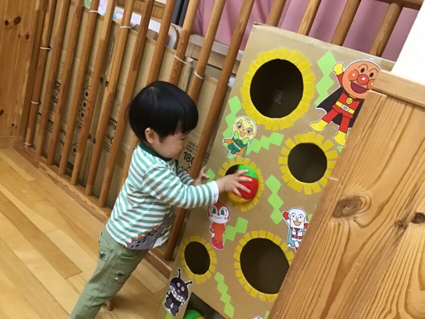 先生が作ってくれたたんぽぽ組のたんぽぽの花と大好きなアンパンマンが貼ってある
所にボールを入れると「ころん♪」と音がして下に落ちていくのが楽しくて何度も繰り返して遊んでいます。
遊戯室にも行って、大きな三角マットの滑り台で滑る感覚を楽しんだり、ボルダリングに触ってみたり。
雨の日でも身体を使って遊ぶことが出来ています。