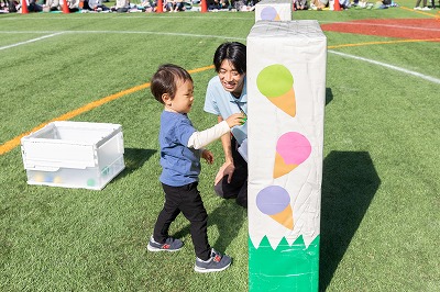 ２歳児さんは今年は初めて保護者と離れて競技に参加しました。<br />
ジャンプも１歳児さんの時よりも高い所から出来るようになりました。<br />
大好きなノラネコぐんだんの絵本からアイスに見立てたボールを猫にあげることも<br />
出来るようになりました。<br />
２歳児さんは目標物に向かって運ぶ、入れる等の運動遊びをすると共に、<br />
限られた空間でジャンプすることも遊びの中で取り入れてきたので、フラフープの<br />
中でも上手にジャンプする事が出来ました♪