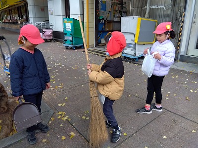 園舎の前の紅葉がとてもきれいな季節になりました。<br />
子どもたちは落ち葉の音を楽しみながら散歩へ出かけます。<br />
「落ちた葉っぱは誰が綺麗にしてくれているんだろう？」<br />
そこで先生と子どもたちが一緒に考えて自分たちの園の前は自分たちでも掃除をしてみることにしました。<br />
初めて使う竹ぼうきは大きくて重かったけれど、たくさんの葉を履き集める事を<br />
体験出来ました。<br />
このような経験からも子どもたちが環境に興味を持てるようにしています。