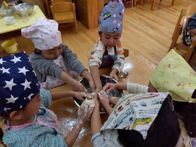 4歳児さんが食育でうどん作り、出汁作り、あんこ作りをしました。
うどんの生地作りでは生地の感触が、どんどん変化していく工程に驚きながら
こねて、伸ばして、切ることを経験しました。
出汁比べでは素材の香りを味わいながら、出汁ならではの風味を感じていました。
香りの違いに気づきながらも少し苦手そうにする子どもたちも見られましたが
、給食のお味噌汁が出汁から出来ていることを聞くと
「えっ?どうだったんだ!」「じゃあ、これ好きかも。」
と笑顔を見せてくれました。
様々な食育を経験し、食材への興味の他に、いつも作ってくれる調理さんへの感謝の気持ちも芽生えているようでした。