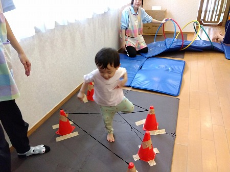 でこぼこしたマットの上を歩いたりゴムひもをまたいだりすることで バランス感覚を養っています。 足元をよーく見ながらバランスをとることがポイントです。